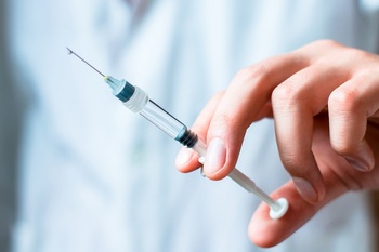 врач держит в руках шприц